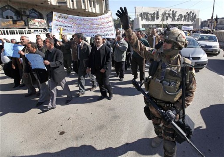 An Iraqi army soldier gestures during a demonstration against a lack of basic services near Tahrir Square in Baghdad, Iraq, on Sunday. The banner in Arabic says that the protesters are asking for jobs and also details the dismissal of more than 1200 employees of the Ministry of Electricity. 